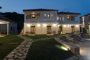 a house with a stone walkway in front of a yard at Imathoessa in Gialova