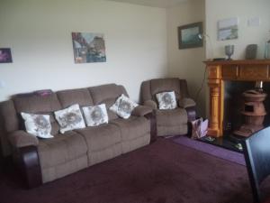 a living room with a couch and a fireplace at Sea Breeze in Canower