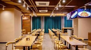 uma sala de jantar com mesas e cadeiras e um grande ecrã em Liyuan Hotel em Shenzhen