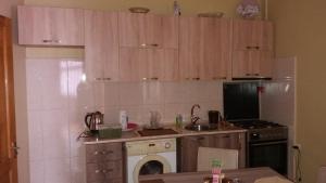 a kitchen with wooden cabinets and a sink and a dishwasher at Guest House kartvelishvili in Batumi