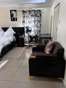 a bedroom with a bed and a couch and a chair at My Home Suites Area14 in Lilongwe +3 photos