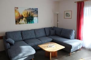 Ferienhaus Nr 124, Kategorie Economy, Feriendorf Hochbergle, Allgäu في Karlsebene: غرفة معيشة مع أريكة زرقاء وطاولة قهوة