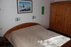 Ferienhaus Nr 124, Kategorie Economy, Feriendorf Hochbergle, Allgäu في Karlsebene: غرفة نوم بسرير خشبي وخزانة خشبية