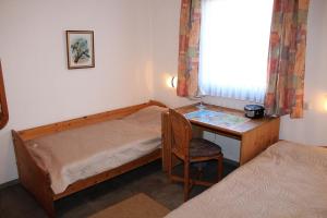 Ferienhaus Nr 124, Kategorie Economy, Feriendorf Hochbergle, Allgäu في Karlsebene: غرفة نوم مع مكتب وسرير وكرسي