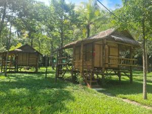 a couple of huts in a field with trees at Koh kood Good Time by Jasmine in Ko Kood