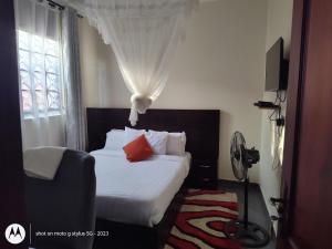 una camera da letto con un letto con lenzuola bianche e cuscini rossi di Sonkoyaz bed and breakfast a Entebbe