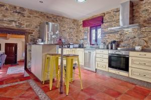 eine Küche mit Steinwänden und gelben Hockern in der Unterkunft Casa Rural Ucedo in Ucedo