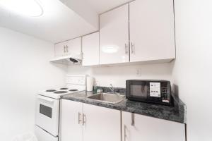 a white kitchen with a microwave and a sink at Cozy Private 2 bedroom apartment, free Wifi, free parking in heart of Toronto, surrounded by nature in Toronto