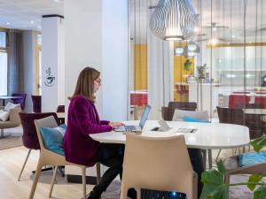 a woman sitting at a table with a laptop at Mercure Nice Centre Grimaldi in Nice