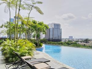 a swimming pool with chaise lounge chairs and palm trees at 45 Antasari Suite powered by Cocotel in Jakarta