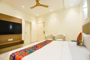 a bedroom with a large bed and a flat screen tv at FabHotel Dev Palace I - Pitampura in New Delhi
