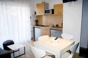 a small kitchen with a white table and chairs at Résidence Thalacap in Cap d'Agde