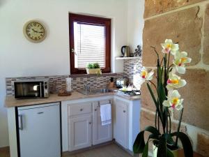 a kitchen with a sink and a clock on the wall at La Casetta Holiday Home in Alghero