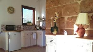 kuchnia z białymi szafkami i kamienną ścianą w obiekcie La Casetta Holiday Home w mieście Alghero +14 zdjęć