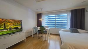 a living room with a television and a dining table at Paradise Hongdae in Seoul