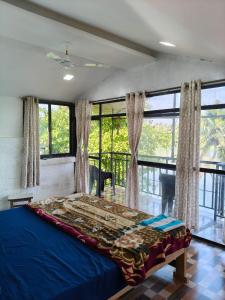 a bedroom with a blue bed and large windows at RivoGoa riverside Homestay in Bardez