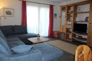 Ferienhaus Nr 125, Kategorie Economy, Feriendorf Hochbergle, Allgäu في Karlsebene: غرفة معيشة مع أريكة زرقاء وتلفزيون