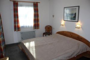 Ferienhaus Nr 125, Kategorie Economy, Feriendorf Hochbergle, Allgäu في Karlsebene: غرفة نوم بها سرير ونافذة وكرسي