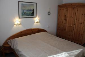 Ferienhaus Nr 125, Kategorie Economy, Feriendorf Hochbergle, Allgäu في Karlsebene: غرفة نوم مع سرير وخزانة خشبية