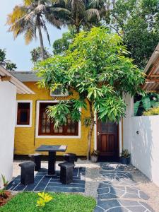 een picknicktafel voor een geel huis bij Madu - Guesthouse & Local Restaurant in Weligama