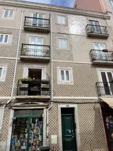 a large brick building with a green door and windows at Central Lisbon Apartment Santos Walk to Cais do Sodré in Lisbon