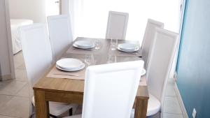 a dining room table with white plates and chairs at Résidence Thalacap in Cap d'Agde