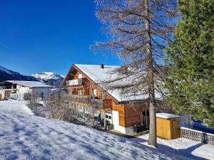 ein Blockhaus im Schnee mit einem Baum in der Unterkunft Neunerköpfle in Tannheim