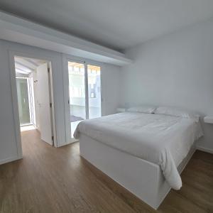 una camera bianca con un letto e una porta scorrevole in vetro di Bungalows Villas Blancas a Puerto del Carmen