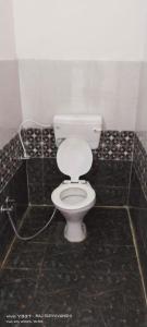 Un baño con inodoro blanco en una habitación embaldosada. en Hotel Trilochan, en Sehore