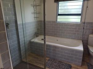 a bathroom with a shower and a tub and a toilet at Carshalton Cottage in Mooirivier