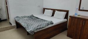 1 dormitorio con cama con marco de madera y mesita de noche en Hotel Trilochan, en Sehore
