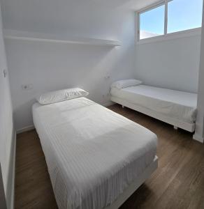 two beds in a white room with a window at Bungalows Villas Blancas in Puerto del Carmen