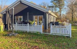 a small house with a fence and an umbrella at Beautiful Home In Oksbøl With Sauna in Øster Vrøgum +17 photos