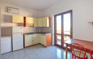 een keuken met een tafel, een koelkast en een raam bij Pet Friendly Apartment In Briatico in Pannaconi