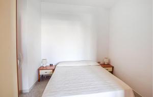 een kleine witte kamer met een bed en twee tafels bij Pet Friendly Apartment In Briatico in Pannaconi +3 foto's