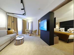 a hotel room with a bed and a couch and a tv at Mercure Grenoble Centre Porte des Alpes in Grenoble