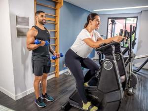 un hombre y una mujer en una bicicleta estática en un gimnasio en Mercure Sao Paulo Berrini, en São Paulo