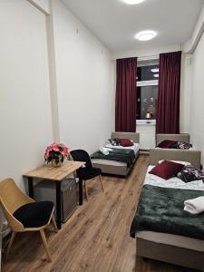 Habitación con 3 camas, mesa y sillas en Hostel KASZUBSKA, en Wroclaw