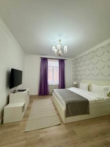 a white bedroom with a bed and a television at Hotel Astoria in Astana