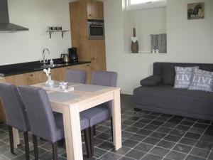 uma cozinha com uma mesa e cadeiras e um sofá em De Zandkant em Biezenmortel