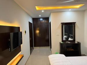 ein Schlafzimmer mit einem Bett, einem Fernseher und einem Spiegel in der Unterkunft Mahnoor Living Apartment Peshawar in Peschawar