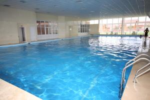 a large indoor swimming pool with blue water at Семейная Вилла in Bayetovka