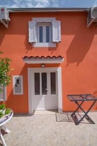 an orange building with a white door and a table at Luisa S2 room B in Veli Lošinj