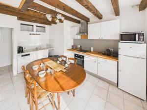 Una cocina con una mesa de madera y gabinetes blancos. en Maison pour 5 - Grande jardin et terrasse - Jacuzzi, en Le Bos de Plazac 14 fotos más