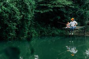 a man standing on a picnic table next to a lake at Lolo's by Raho - Loft Stay in Coorg in Ammatti