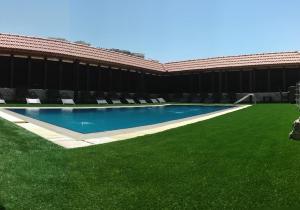 a swimming pool with green grass next to a building at Seven Wonders Hotel in Wadi Musa