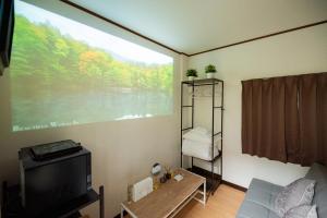 a living room with a tv and a large window at マエカワビル403Private In-Room Theater in Osaka