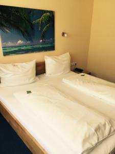 una cama con sábanas blancas y una pintura en la pared en Hotel Gerber, en Hösbach