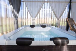 Eine Badewanne mit zwei Hockern vor einem großen Fenster in der Unterkunft Glamping Happiness - Natural Pool & Wellness in Ribnica + 20 Fotos