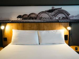 Un dormitorio con una cama blanca con un cuadro en la pared. en Ibis Valladolid, en Valladolid 201 fotos más